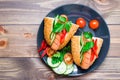 Ready-to-eat hot dogs from fried sausages, sesame buns and fresh vegetables on a plate on a wooden table Royalty Free Stock Photo