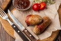 Ready-to-eat pigs sausages wrapped in bacon on wooden board. Fried savory sausages wrapped in bacon served with onion Royalty Free Stock Photo