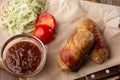 Ready-to-eat pigs sausages wrapped in bacon on wooden board. Fried savory sausages wrapped in bacon served with onion Royalty Free Stock Photo