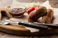 Ready-to-eat pigs sausages wrapped in bacon on wooden board. Fried savory sausages wrapped in bacon served with onion Royalty Free Stock Photo