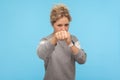 Ready to fight! Feisty woman with short curly hair in sweatshirt punching in front of camera, attacking and looking aggressively