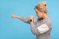 Ready to fight! Side view of feisty woman with short curly hair in sweatshirt punching to side with aggressive expression Royalty Free Stock Photo