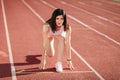 Ready to go! Female athlete in shorts and tank tops on the starting line of a stadium track, preparing for a run. Fitness girl is Royalty Free Stock Photo