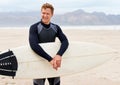 Ready to hit the waves. A young surfer smiling as he holds his surfboard on the beach. Royalty Free Stock Photo