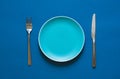 Color plate fork and knife isolated on blue background. Royalty Free Stock Photo