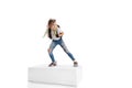 Full-length portrait of smiling girl in casual clothes standing on big box isolated on white studio background. Happy Royalty Free Stock Photo