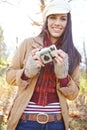 Ready to snap some photos. A beautiful young woman standing outdoors in the woods while holding her camera and smiling