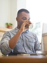 Ready to tackle his work. A young man drinking coffee while using his laptop at a cafe. Royalty Free Stock Photo