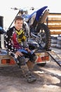 Ready to take on anything. Portrait of a young dirt bike racer sitting on trailer with his bike. Royalty Free Stock Photo