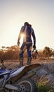 Ready to take on anything. Rearview shot of a motocross rider standing in front of his dirtbike.