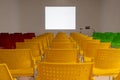 Ready to use rows of colorful chairs in conference room with blank white space on wall as projector screen Royalty Free Stock Photo