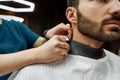 Ready to work. Close up shot of a handsome bearded man sitting in barbershop chair. Barber girl or female hairdresser Royalty Free Stock Photo