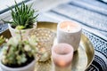 Real apartment interior decor, aromatic candles and plants on vintage tray with pillows and blanket on white windowsill