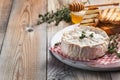 A real Camembert from France with thyme, honey and toasted bread on old wooden rustic table. Soft cheese on a wooden background wi Royalty Free Stock Photo