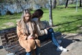 Real couple of young women, sitting on a bench, back to back and checking social networks on their cell phones. Concept lgtbiq+, Royalty Free Stock Photo