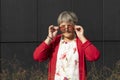 Real Cute Senior Old 70s Woman Looking Over Sunglasses Outdoor In Summertime, Dark Wall on Royalty Free Stock Photo