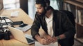 Real dedication doesnt quit. a young businessman writing in a notebook and using a laptop with headphones during a late