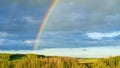 A real double rainbow in a cloudy sky after heavy rain. A rare natural phenomenon in the blue sky. Rainbow over hilly countryside