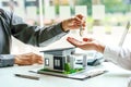 The real estate agent gives the buyer the house keys on a table with modern miniature house model Royalty Free Stock Photo