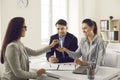 Real estate agent gives the keys to her new home to a married couple at a meeting in the office.