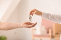 Real estate agent giving keys from house to new owner indoors