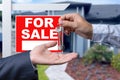 Real Estate Agent Handing Over the House Keys in Front of a Beautiful New Home and For Sale Real Estate Sign. Royalty Free Stock Photo