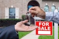 Real Estate Agent Handing Over the House Keys in Front of a Beautiful New Home and For Sale Real Estate Sign. Royalty Free Stock Photo