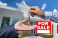 Real Estate Agent Handing Over the House Keys in Front of a Beautiful New Home and For Sale Real Estate Sign. Royalty Free Stock Photo