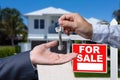 Real Estate Agent Handing Over the House Keys in Front of a Beautiful New Home and For Sale Real Estate Sign. Royalty Free Stock Photo