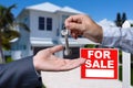 Real Estate Agent Handing Over the House Keys in Front of a Beautiful New Home and For Sale Real Estate Sign. Royalty Free Stock Photo