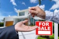 Real Estate Agent Handing Over the House Keys in Front of a Beautiful New Home and For Sale Real Estate Sign. Royalty Free Stock Photo