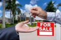 Real Estate Agent Handing Over the House Keys in Front of a Beautiful New Home and For Sale Real Estate Sign. Royalty Free Stock Photo