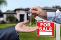 Real Estate Agent Handing Over the House Keys in Front of a Beautiful New Home and For Sale Real Estate Sign. Royalty Free Stock Photo