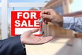 Real Estate Agent Handing Over the House Keys in Front of a Beautiful New Home and For Sale Real Estate Sign. Royalty Free Stock Photo