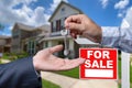 Real Estate Agent Handing Over the House Keys in Front of a Beautiful New Home and For Sale Real Estate Sign. Royalty Free Stock Photo