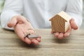 Real estate agent holding house figure and key at table, closeup