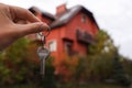 Real estate agent holding keys to new house outdoors, closeup. Space for text Royalty Free Stock Photo