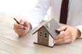 Real estate agent with house model at wooden table. Mortgage concept Royalty Free Stock Photo