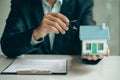 Real estate agent ideas about renting and buying a house, the employee is offering a contract of sale and with the house model on Royalty Free Stock Photo