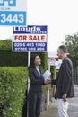Real Estate Agent And Man Shaking Hands By Sale Signs