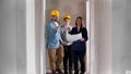 A real estate agent showing a new draft apartment to a young married couple in helmets - looking around Royalty Free Stock Photo