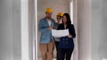 A real estate agent showing a new draft apartment to a young married couple in helmets - looking at the paper Royalty Free Stock Photo