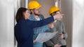 A real estate agent showing a new draft apartment to a young successful married couple holding a layout on the paper Royalty Free Stock Photo