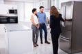 Real Estate Agent Showing Refrigerator In House To A Couple Royalty Free Stock Photo
