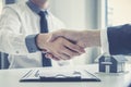 Real estate agents and customers shake hands to congratulate on signing a contract to buy a house with land and insurance