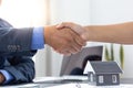 Real estate agents and customers shake hands to congratulate on signing a contract to buy a house with land and insurance