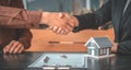 Real estate agents and customers shake hands to congratulate on signing a contract to buy a house with land and insurance