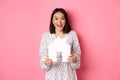 Real estate. Amazed asian woman searching for flat, holding house model and looking at camera happy, standing over pink Royalty Free Stock Photo