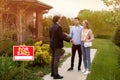 Real estate broker and new home owners in front of their property outdoors Royalty Free Stock Photo