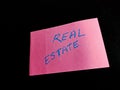 real estate commercial text presented on pink paper slip with blue color alphabets